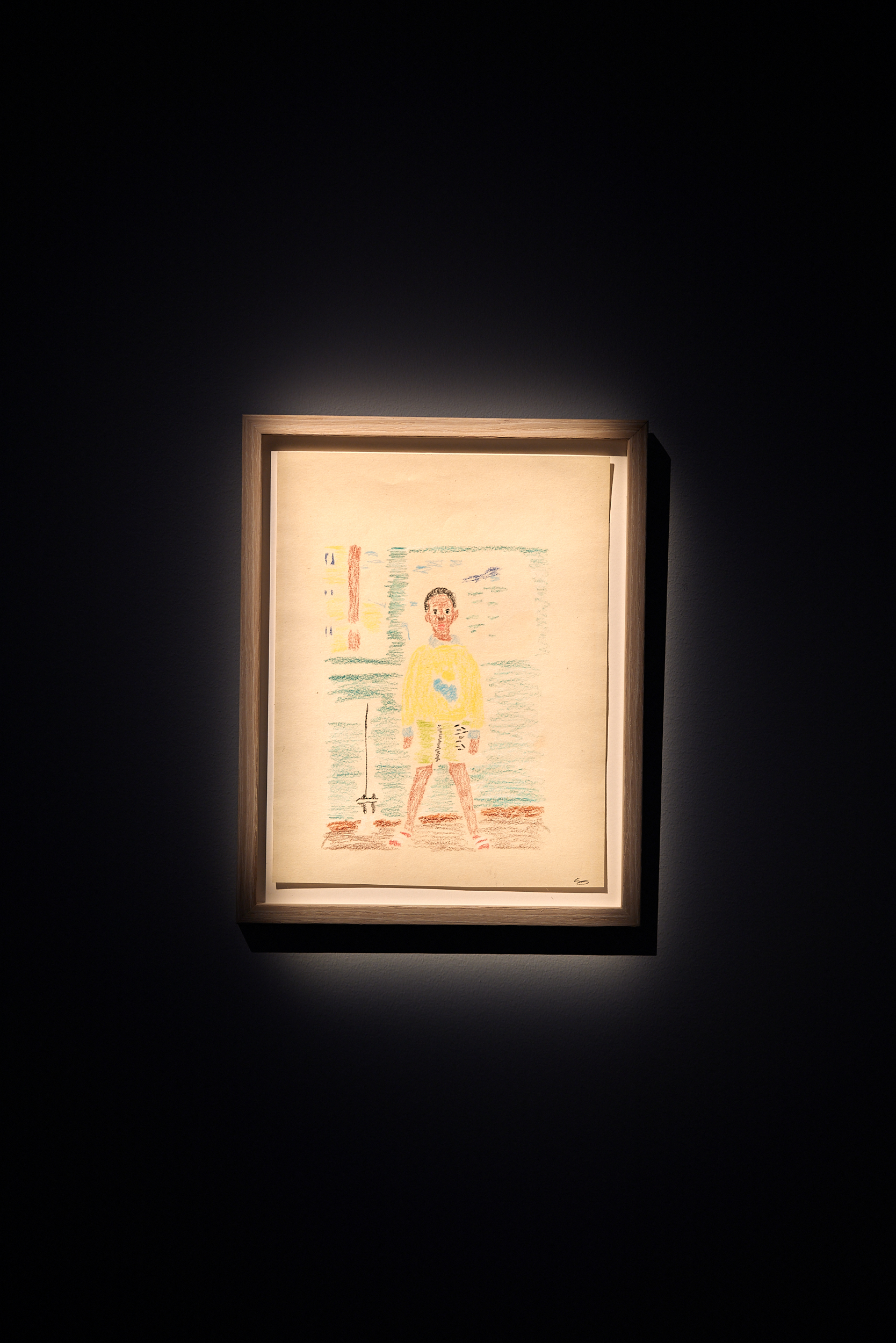 En inramad teckning föreställande ett barn i gul tröja och gula shorts.