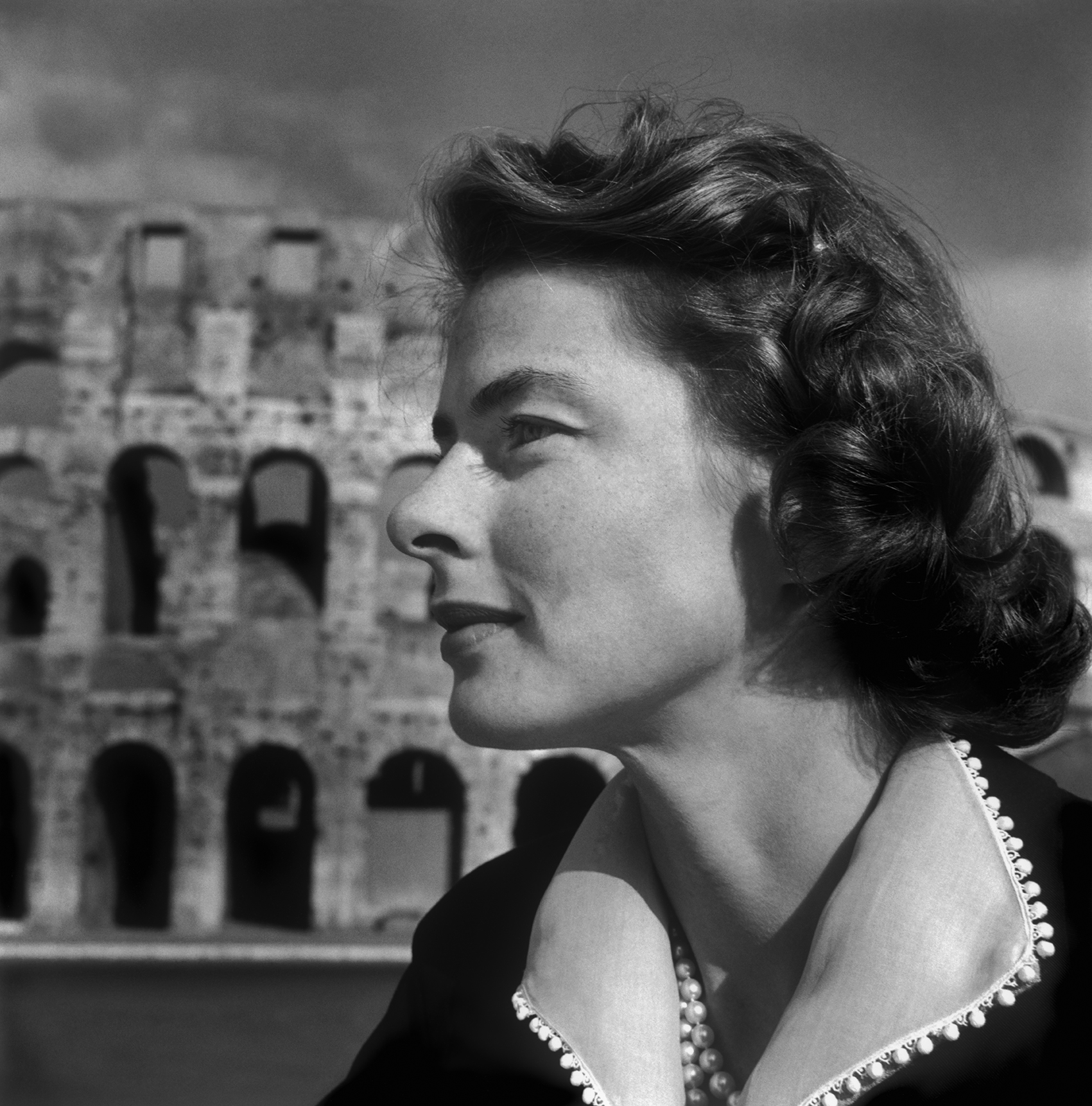 Porträtt i profil av skådespelerskan Ingrid Bergman framför byggnaden Colosseum.