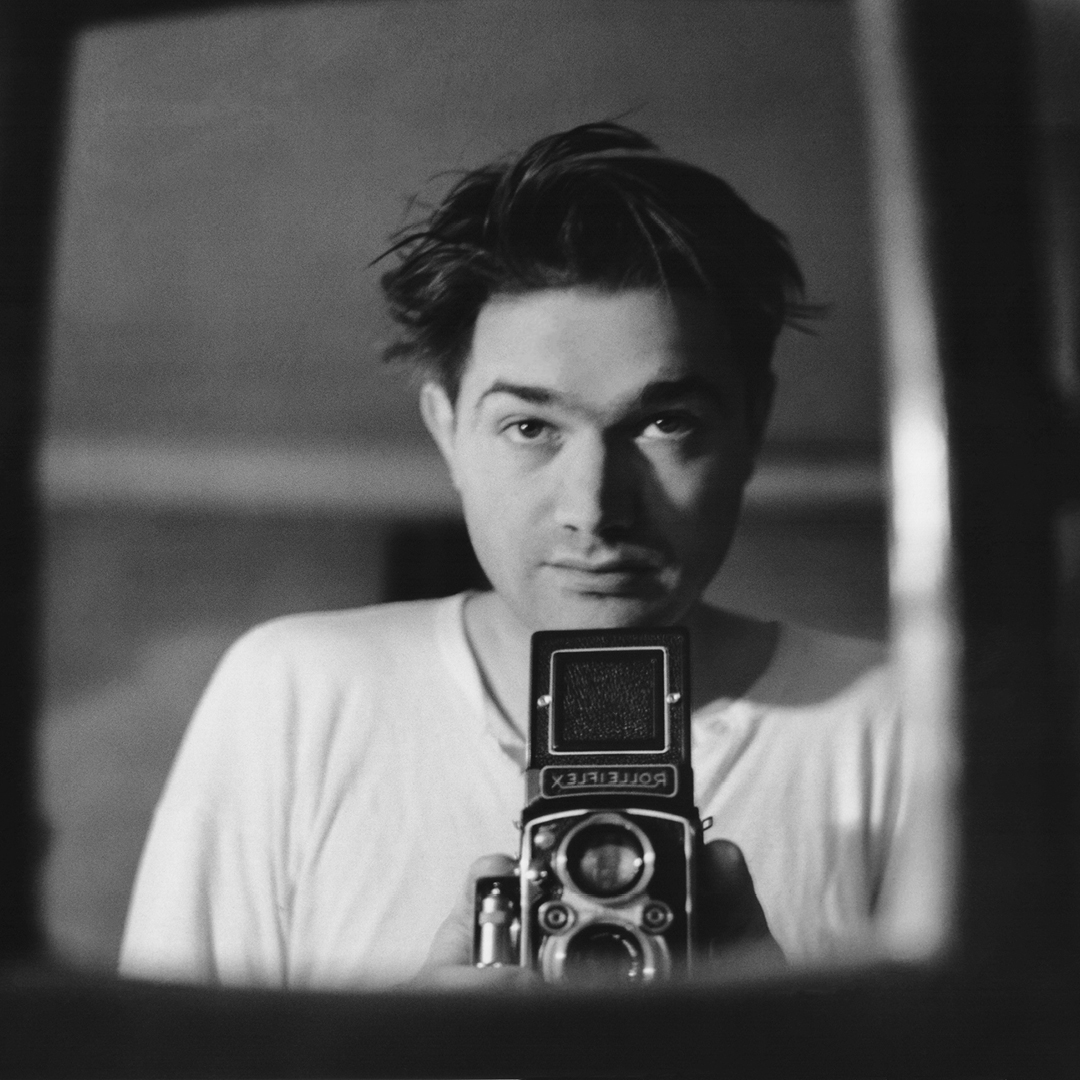En yngre man bakom en kamera av äldre modell.